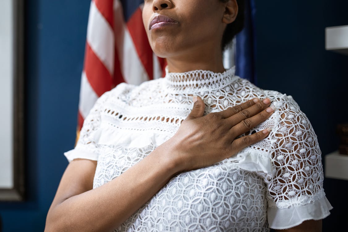 Free A Woman in White Lace Shirt with Hand on Chest Stock Photo