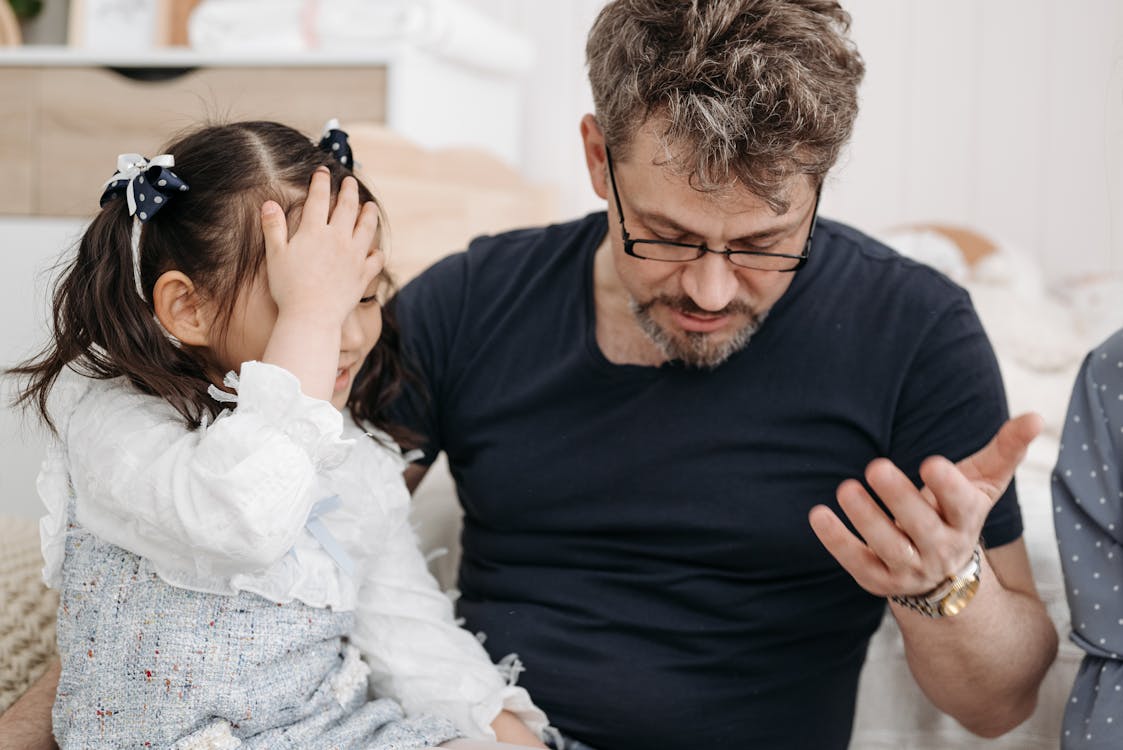 Free Smiling Little Girl Facepalming Because Her Dad Drops Something Stock Photo