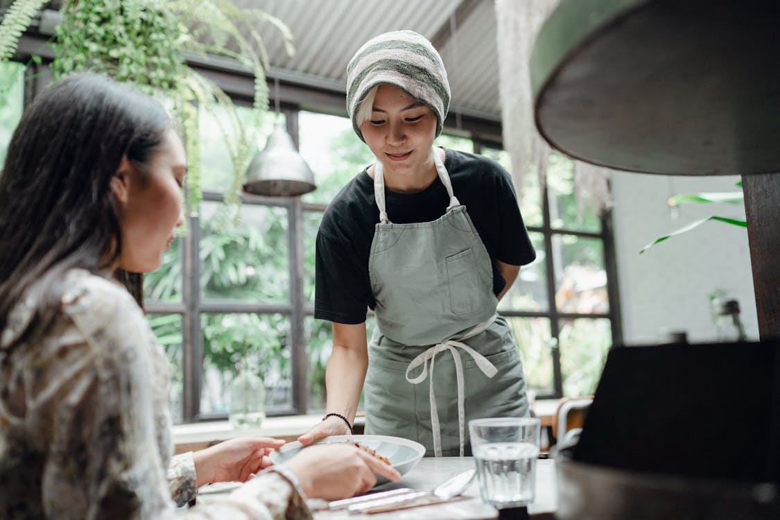 Free Smiling waitress serving food to customer Stock Photo