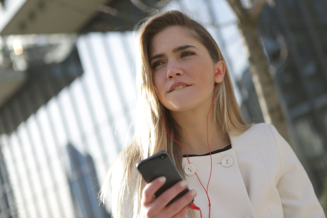 Free Woman In White Blazer Holding Black Smartphone Stock Photo